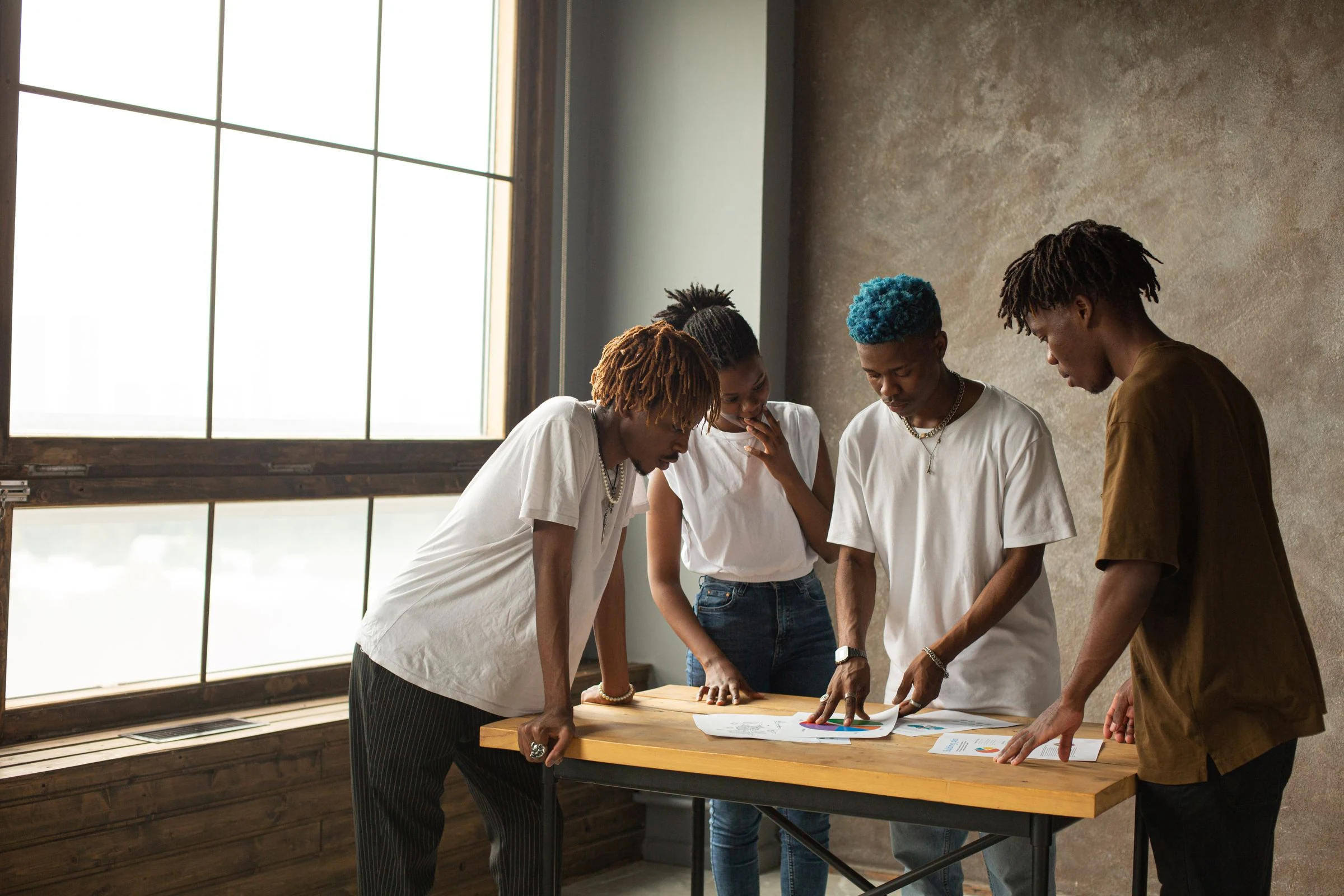Black men and women collaborating on a project around a table in a bright office